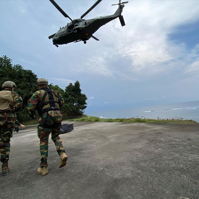 Een NH-90-TTH gevechtshelikopter vliegt over twee militairen tijdens een gezamenlijke oefening in Gabon van land-, lucht- en medische componenten van de Belgische krijgsmacht.