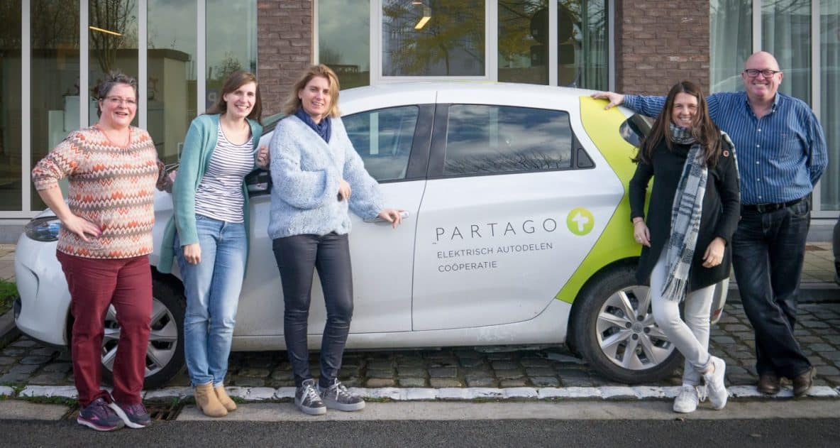 Five people of different age groups and genders posing at a Partago car